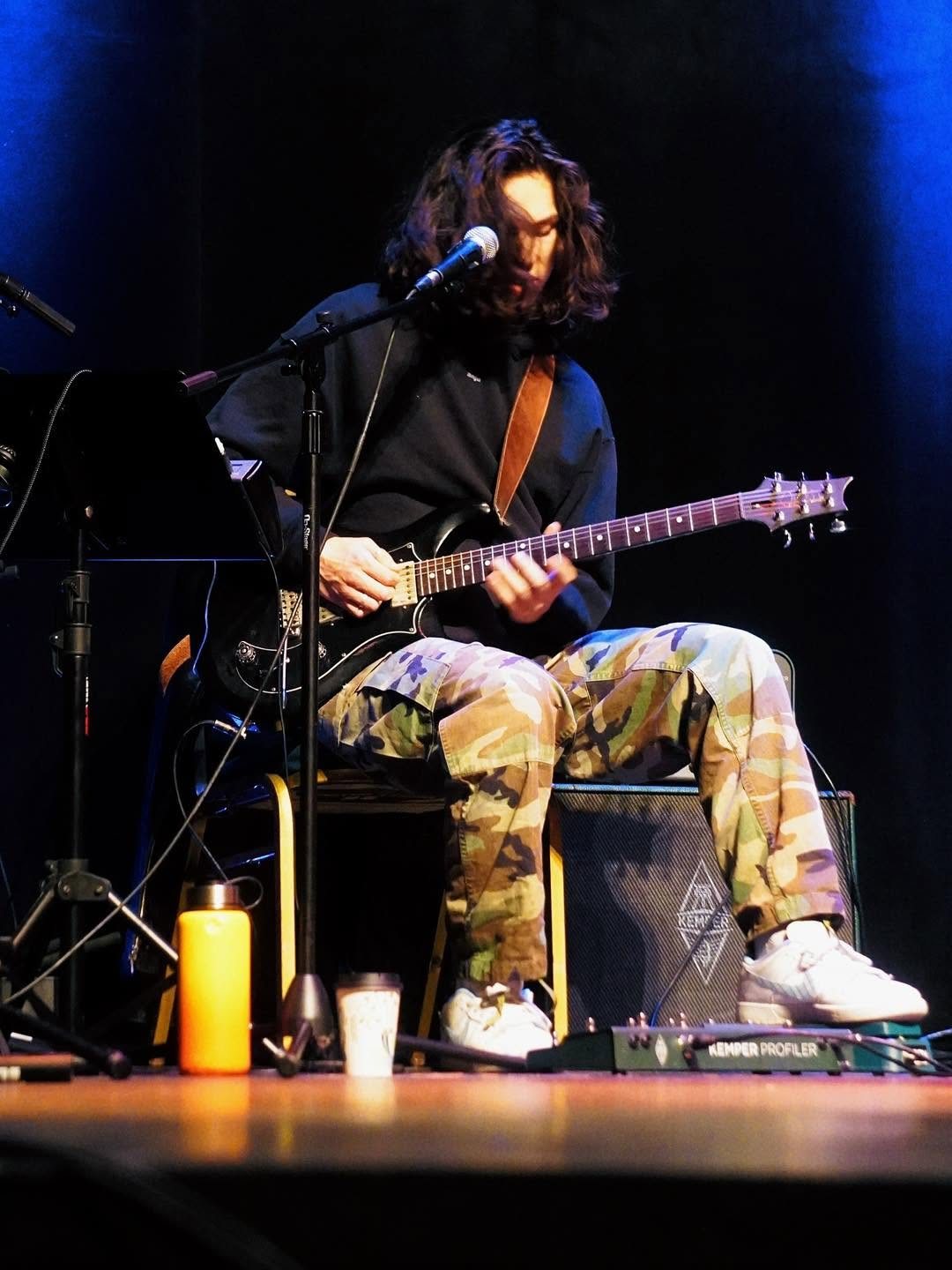 A young musician playing guitar during worship at ICN